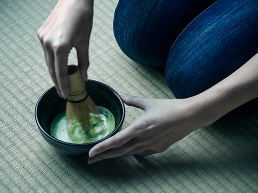 Hands whisking matcha in a tea bowl